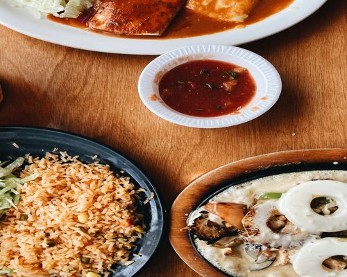 A bowl of fresh traditional Mexican food with beans and tortillas on a wooden table