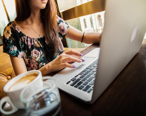 A person typing on a laptop sitting at a modern desk with a coffee mug in an office in Mexico